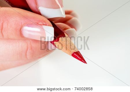 a hand holding a red pen. symbol photo for savings and budget cuts.