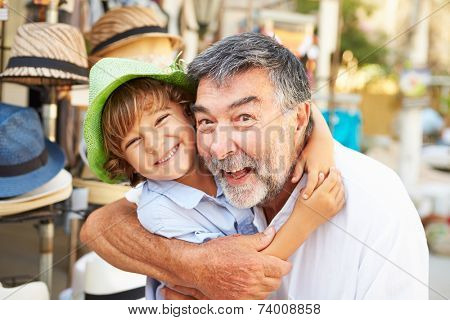 Grandson Trying On Hats With Grandfather At Store