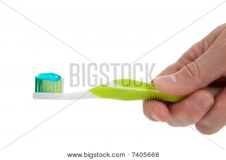 Una mano che tiene uno spazzolino da denti verde su sfondo bianco