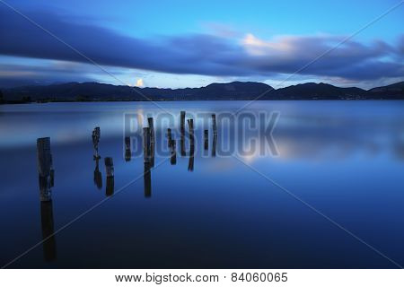 Wooden Pier Or Jetty Remains On A Blue Lake Sunset And Sky Reflection On Water. Versilia Tuscany, It