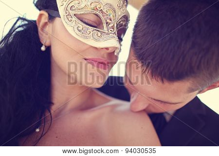 Groom Kissing His Bride. Bride Wearing Venezian Mask