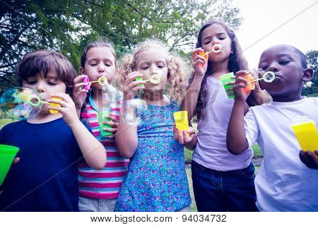 Children playing with bubble wand in the park on a sunny day