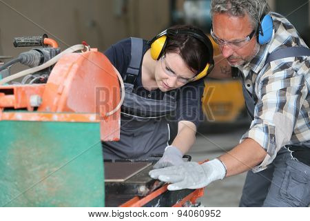 Tiler showing apprentice how to use thermal grinder