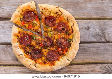 Delicious Baked Salami Pizza Served On Rustic Wooden Table