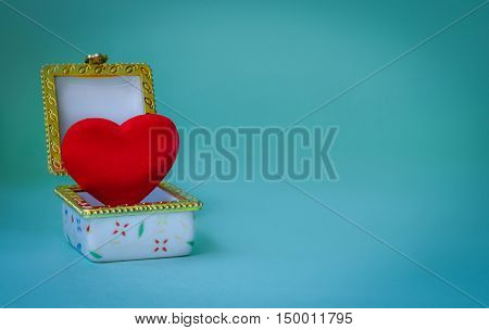 Jewelry box with a red heart inside on blue background