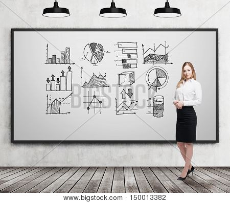 Smiling blond businesswoman standing near whiteboard with graphs on it. Concept of statistics in business.