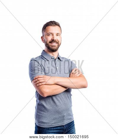 Young handsome hipster man in gray t-shirt, arms crossed, studio shot on white background, isolated