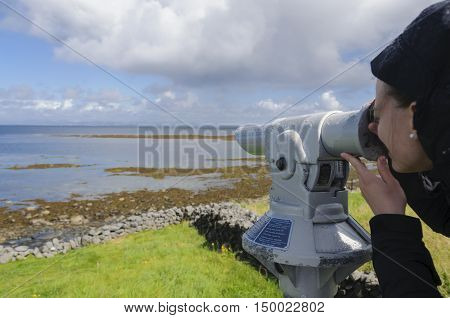 Young girl looking through a coin operated spyglass in Inishmore, Aran Islands, Galway Bay, Ireland, Europe