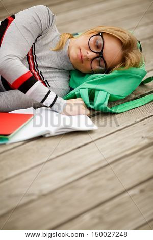 sleeping studenka with open notebook on wooden floor in summer
