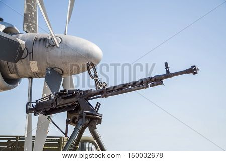 Retro gun on the tripod and optical sight, against the backdrop of the aircraft propellers, close-up. Machine gun outdoors.