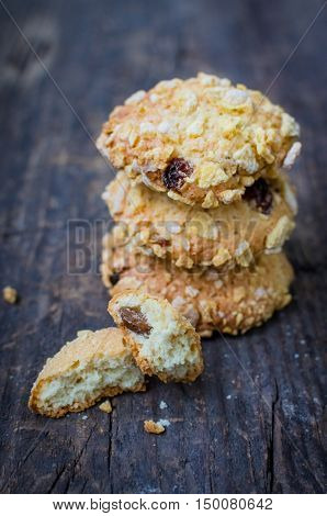 Pile of homemade cornflakes and raisins cookies on old wooden table. Freshly baked corn flake cereal cookies on rustic background. Selective Focus.