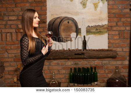 Woman Tasting Wine In Rural Cottage Interior