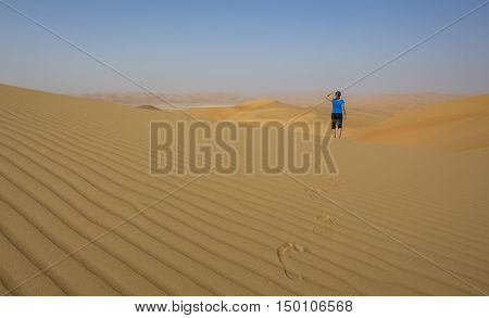Woman walking in Liwa desert, part of Empty Quarter desert