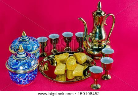 Gold ingot Gold jug Tea glass benjarong on red background.