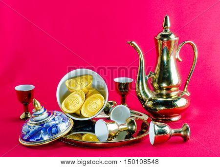 Gold ingot Gold jug Tea glass benjarong on red background.