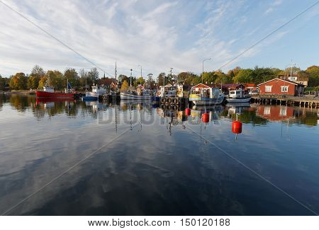 Small fishing boats in the harbor reflecting in the water a perfect sunny windless morning