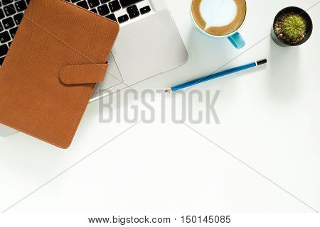 White office desk table with laptop computer pencil cup of coffee and leather notebook. Top view with copy space.Office desk table concept.