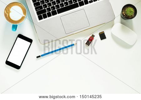 White office desk table with laptop computer pencil cup of coffee flash drive SD card mouse and blank screen smartphone. Top view with copy space.Office desk table concept.