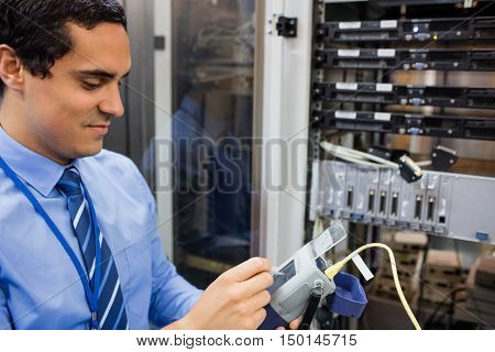 Technician using digital cable analyzer in server room