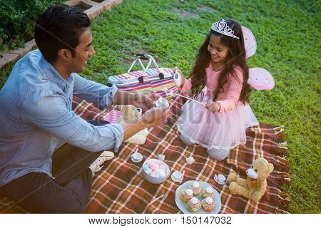 Father and daughter having toy tea party in the garden