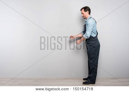 work hard. Pleasant diligent man standing against grey background and working while holding truck