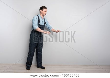 work with pleasure. Pleasant senior man standing against grey background and working while holding truck