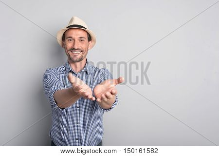 Helpful and generous. Nice delighted bearded man holding his hands in front of him and smiling while sharing something with you