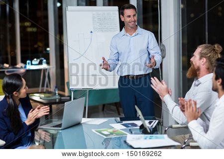 Coworkers applauding a colleague after presentation in the office