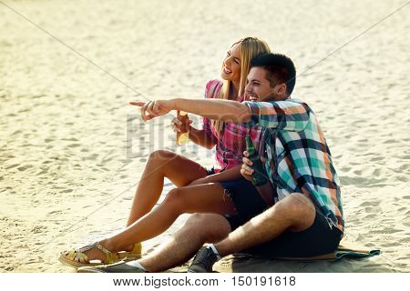 Happy couple drinking beer on the beach.