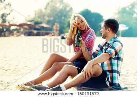 Happy couple drinking beer on the beach.
