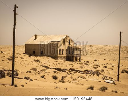 Ghost buildings of old diamond mining town Kolmanskop near Luderitz in Namibia. Abandoned house ruins sunken in the sand dunes of Namib Desert. Vintage toning photography.