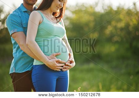 Happy Pregnant Couple At Garden On Magestic Sunset