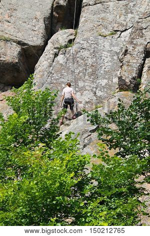 Woman rock climber climbs on a rock
