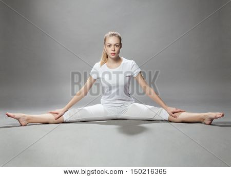 Young Beautiful Woman Makes Exercises On Gray Background