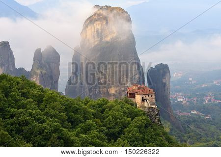 Meteora monasteries. Beautiful view on the Holy Monastery of Roussanov placed on the edge of high rock covered of the morning clouds and mist at sunrise Kastraki Greece