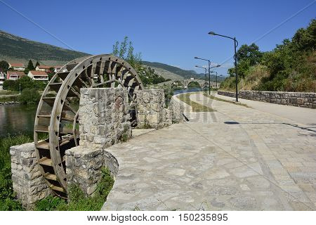 One of the many old water wheels on the Trebisnjica River as it flows through the town of Trebinje in southern Bosnia. The historic 16th century Ottoman Arslanagica Most bridge can be seen in the background.