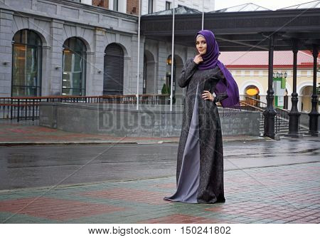 modern Muslim woman in beautiful Eastern dress standing on the background of the hotel. Ufa