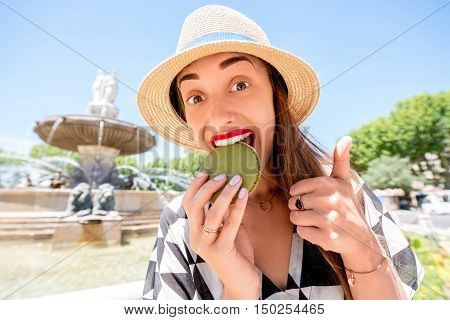 Young female tourist with macaron cookie near the famous fontain de la Rotonde in Aix-en-Provence in France