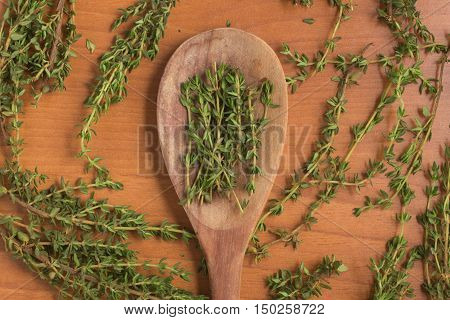 Fresh Thyme into a spoon over a wooden table