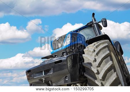 Tractor working on the farm, a modern agricultural transport, a farmer working in the field, tractor in the background cloudy sky, modern tractor closeup