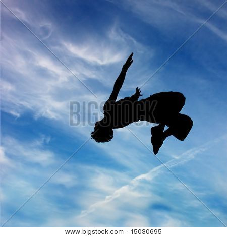 silhouette di saltare l'uomo contro il cielo blu e nuvole