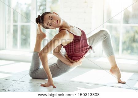 Just do it. Pleasant young slim girl concentrating on her exercise while training hard and stretching her muscles.
