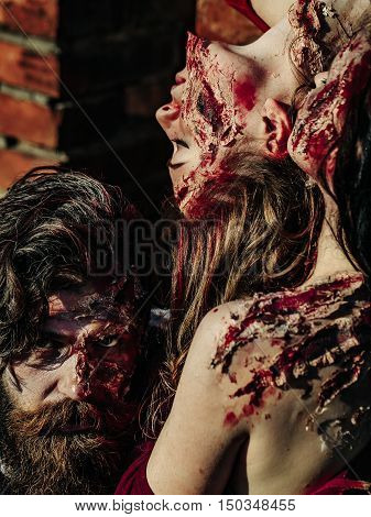 young halloween people zombie of bearded man with beard and sexy pretty girls with red blood and wounds as traditional autumn holiday symbol outdoor