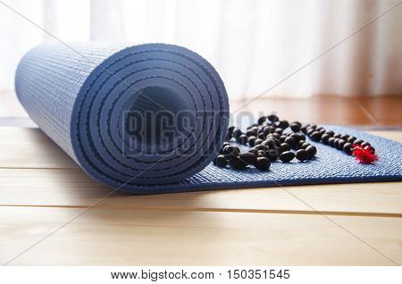 Accessories for yoga and meditation.Mat and mala beads on wooden background.