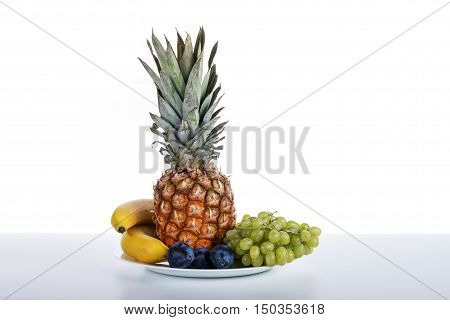 Fruit Bowl On A White Table And White Background In The Photo Studio. Vitamin Deser. Bananas, Plums,