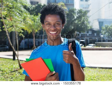 Young african american male student showing thumb outdoor in the city in the summer