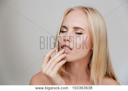 Portrait of a pensive thougtful pretty blonde girl thinking about something isolated on the gray background