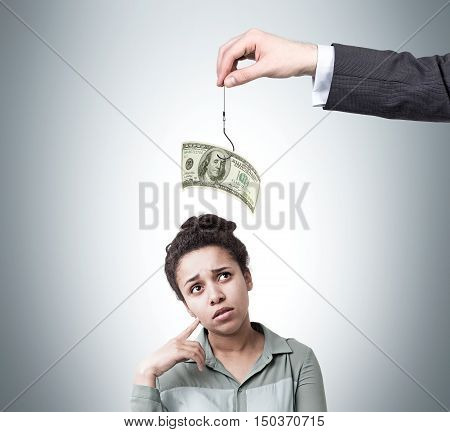 African American girl considering if she should take a bait proposed by businessman. Concept of minimal wage.