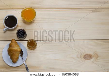 Black coffee orange juice and croissants with different jam on wooden background with copyspace. Concept for breakfast.