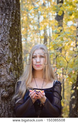 Young Girl In A Fantasy Long Black Dress Posing In An Autumn Forest